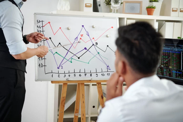 Financial instructor giving a lecture on stock market trading in a classroom environment.