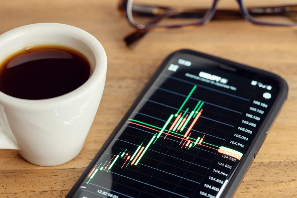 Smartphone showing stock market charts and financial trading applications on the screen.